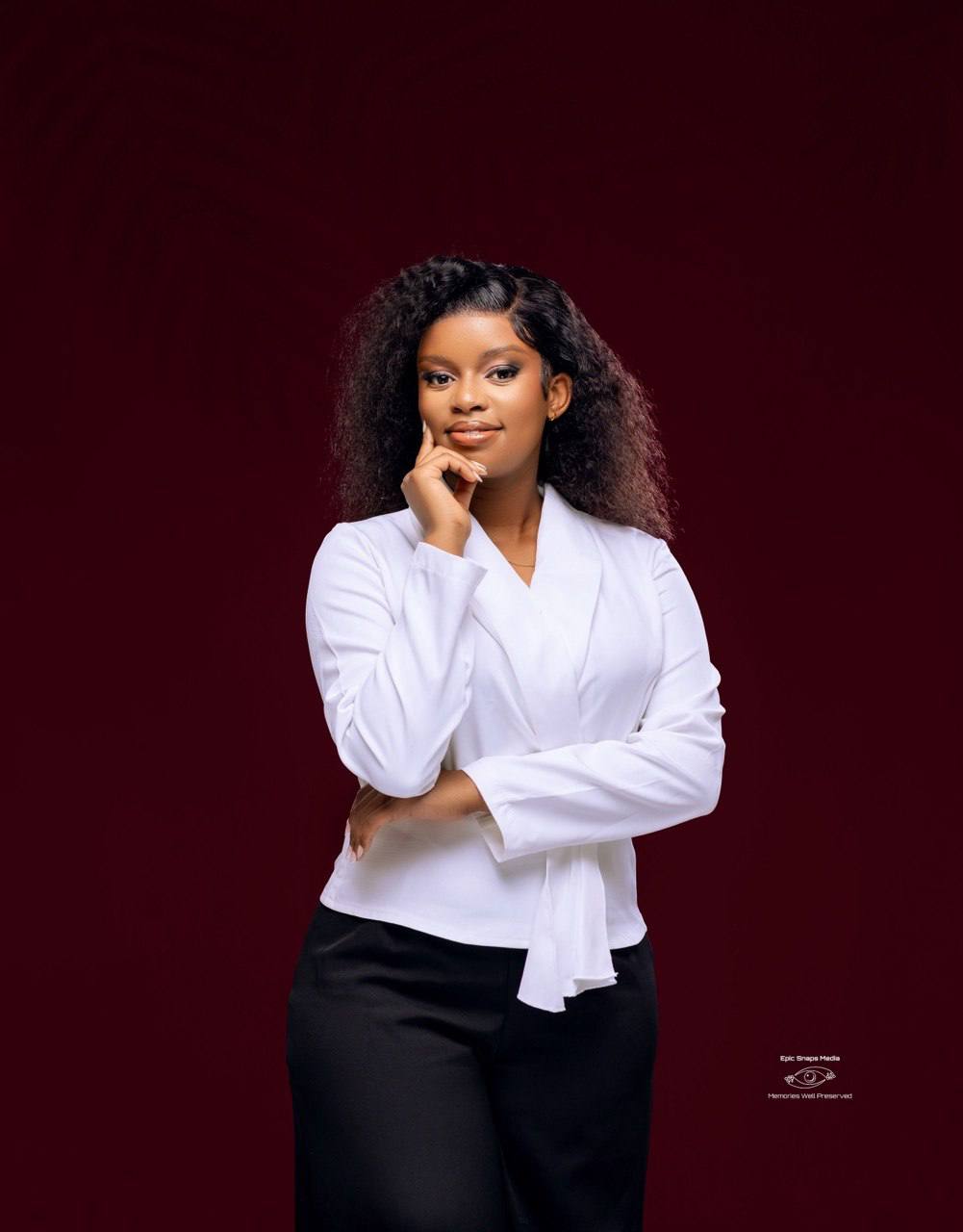 Portrait of Vongayi, the bride, in a white blouse against a deep burgundy backdrop